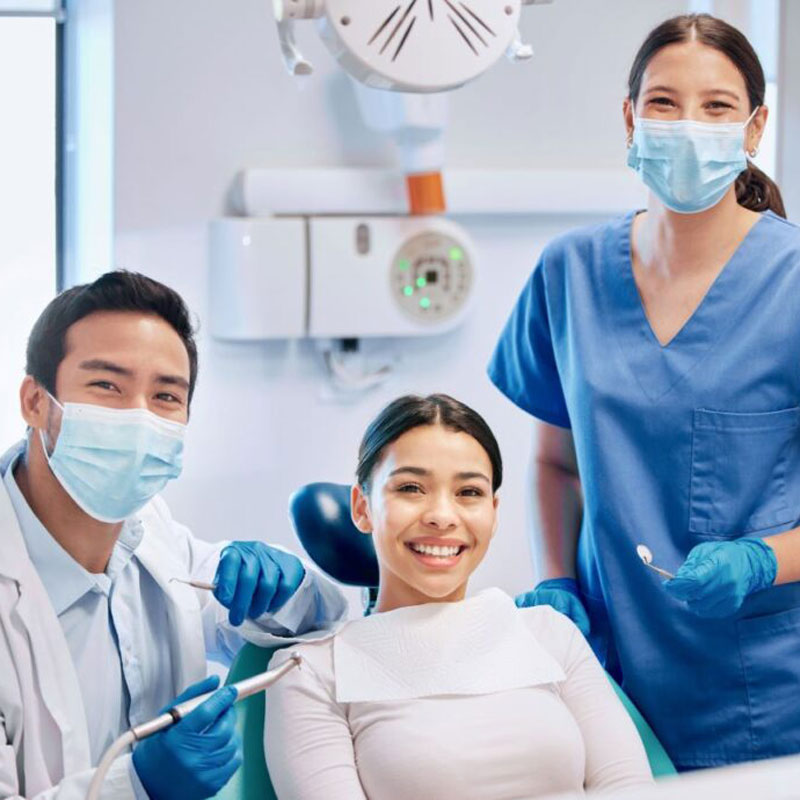 lady smiling in dental chair with dentist on either side