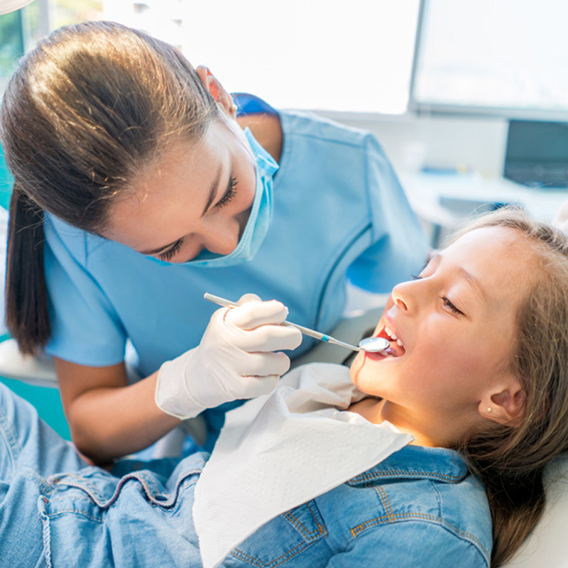 dentist looking at kids teeth in dental chair