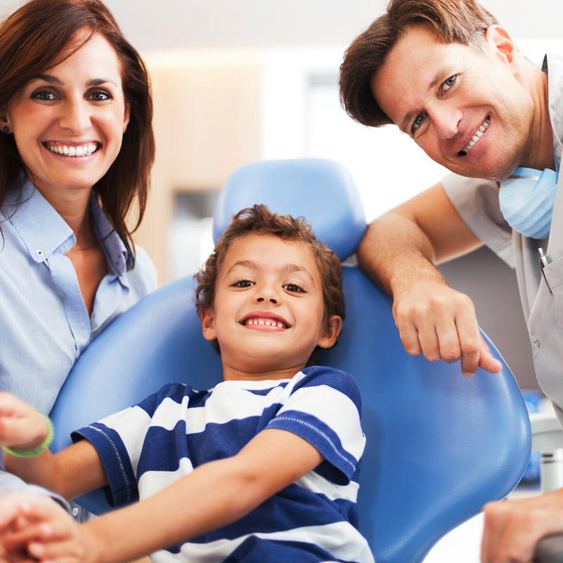 kid in dental chair with people smiling